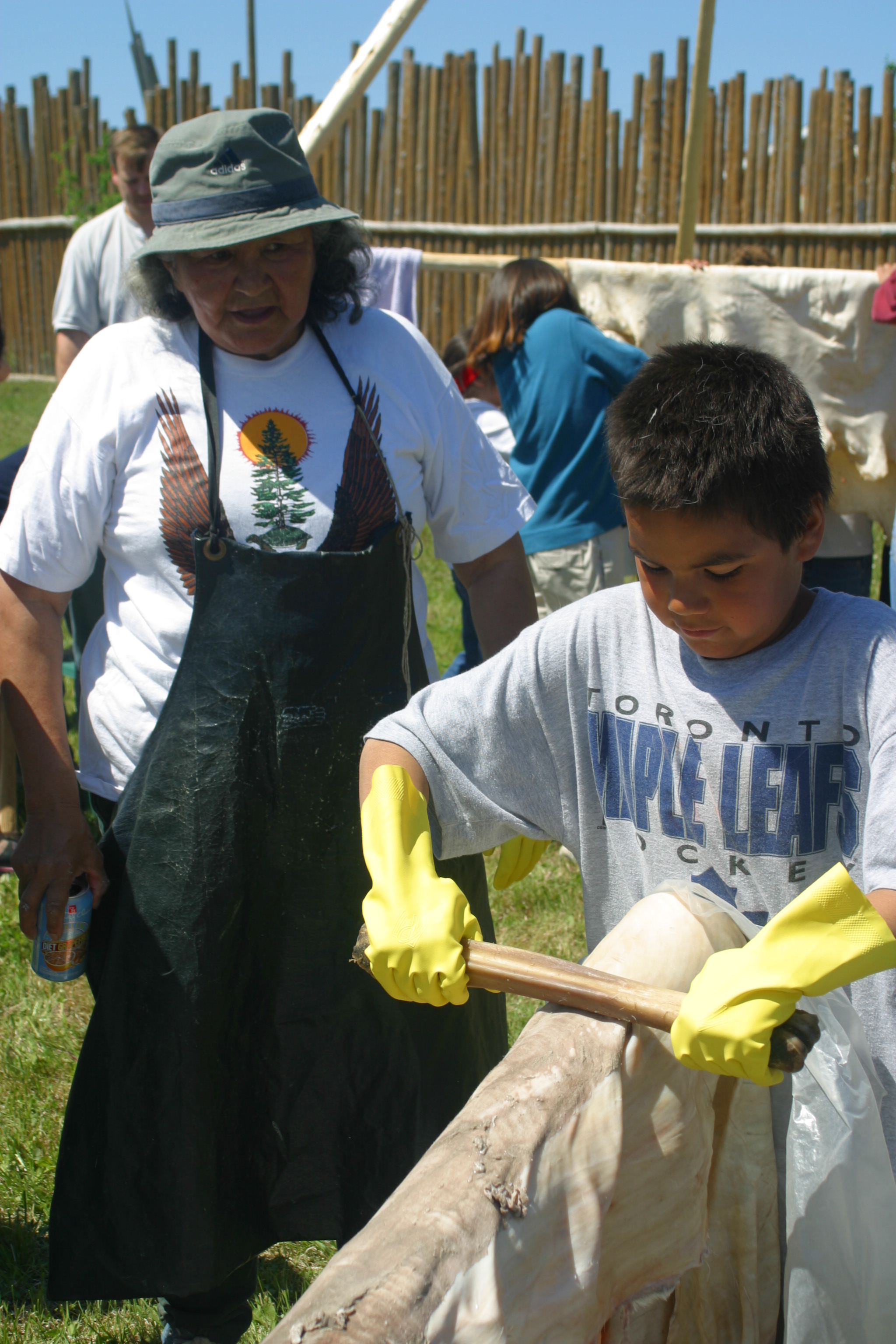 Youth learning how to scrape moose hide
